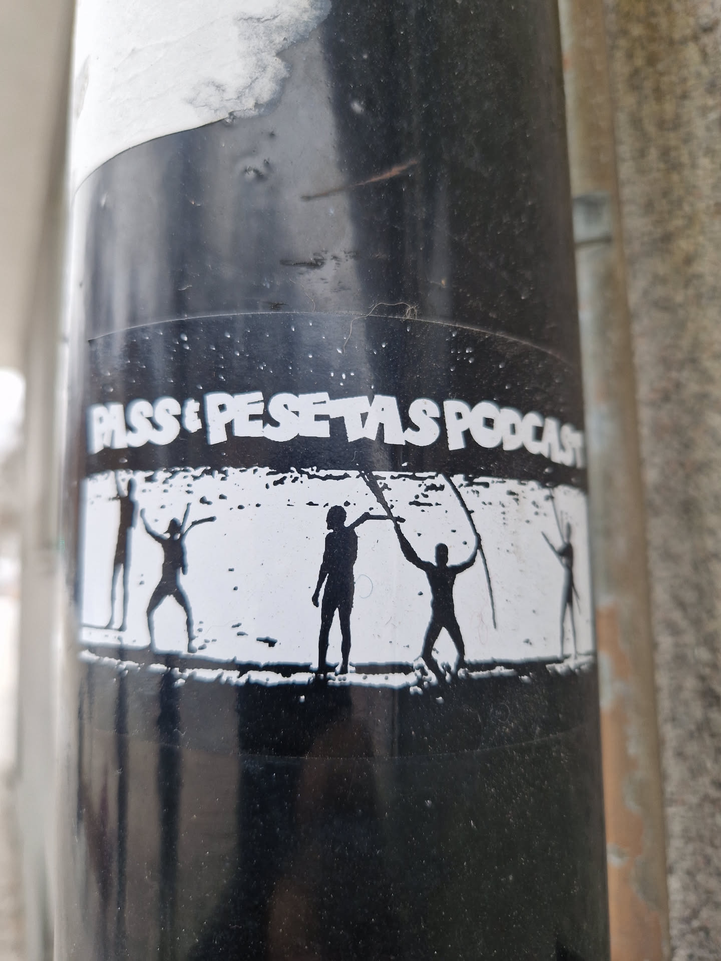 Black and white sticker with the text "Pass i Pessetes Podcast" and an image of four silhouettes of people raising their arms.