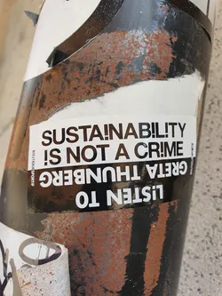 A sticker featuring a quote from Greta Thunberg. The sticker is attached to a rusty surface. The text is in black and white.