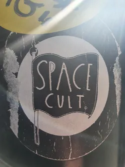 A black and white sticker with a flag design. The flag has the words "SPACE CULT" written on it. The sticker is slightly worn around the edges.