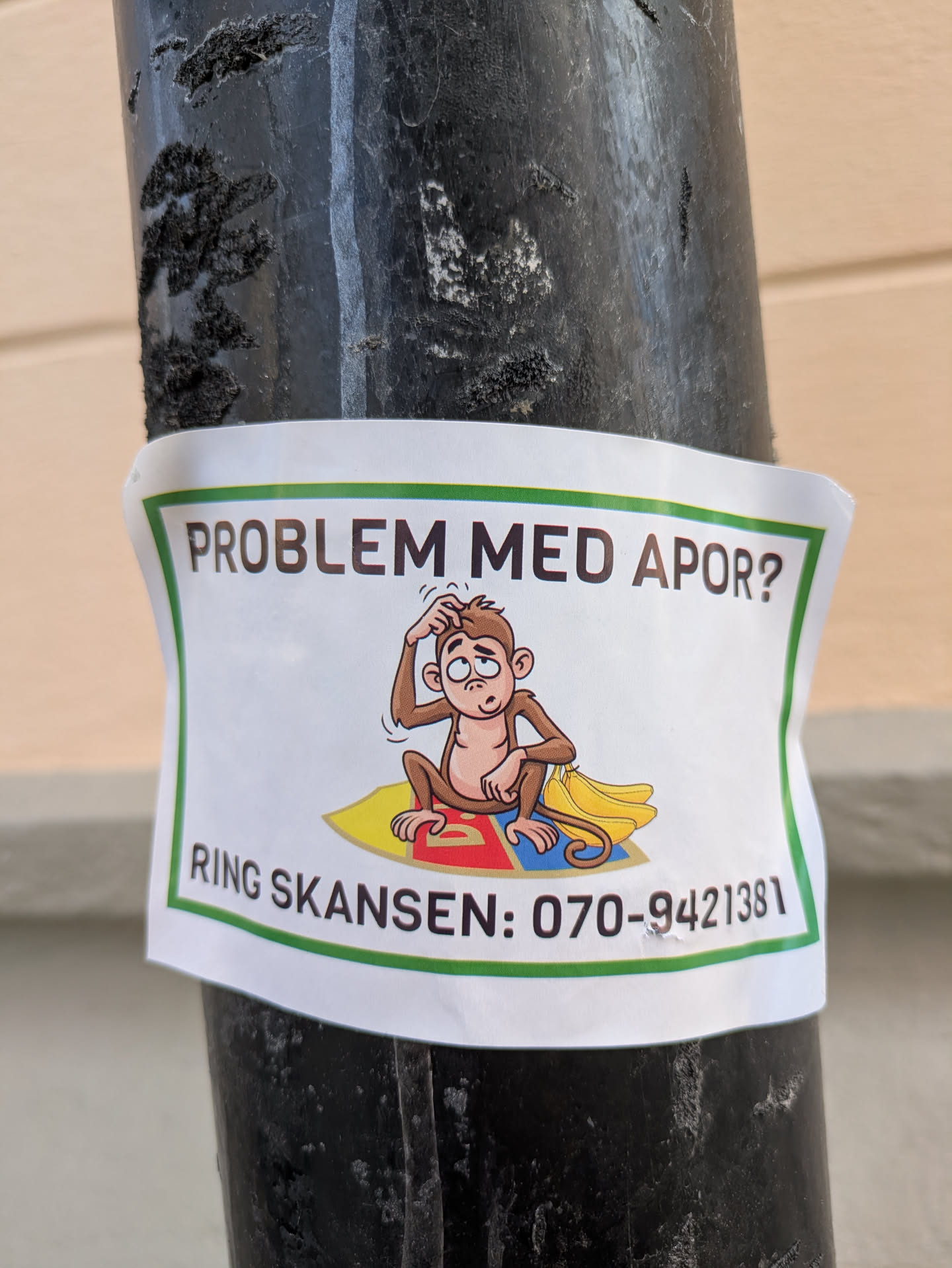 The sticker features a cartoon monkey sitting on a colorful blanket with a banana. The monkey looks puzzled and is scratching its head. The text on the sticker reads "PROBLEM MED APOR? RING SKANSEN: 070-9421381"