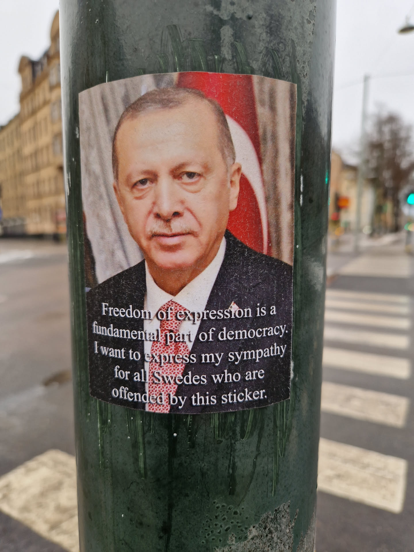A sticker depicting Turkish President Recep Tayyip Erdogan with a text expressing sympathy for anyone offended by it.  The sticker emphasizes freedom of expression as a fundamental part of democracy.