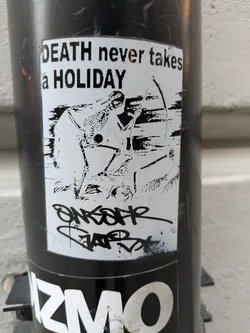 Black and white sticker with an illustration of a skeleton aiming a bow and arrow. The text 'DEATH never takes a HOLIDAY' is written at the top. There is also some graffiti-style tagging at the bottom.