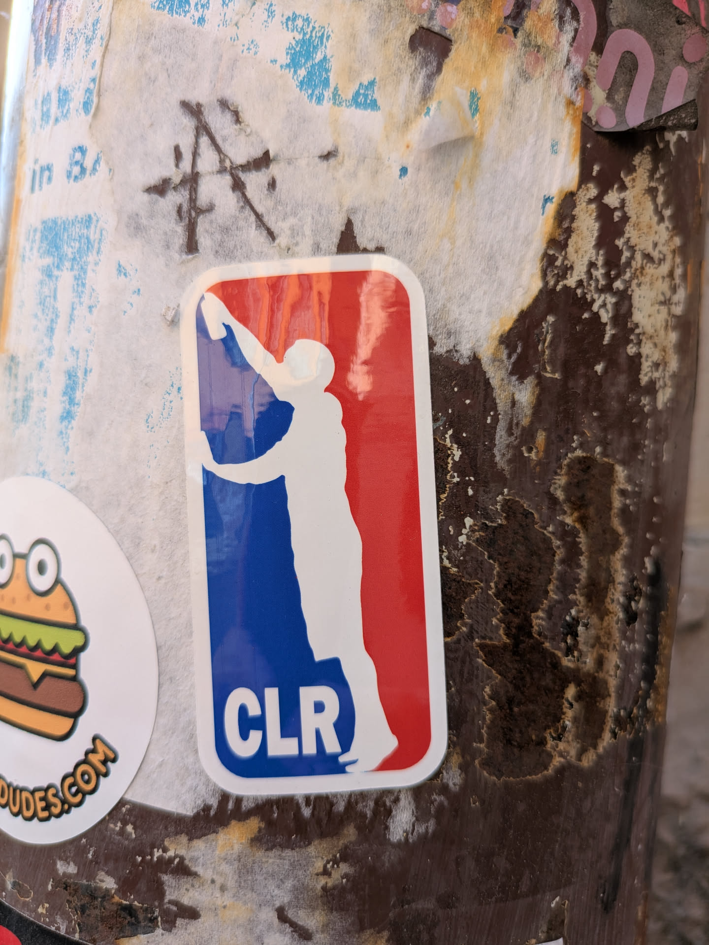 A sticker with a parody of the NBA logo, where the basketball player is replaced by someone reaching for a can, and the letters NBA replaced with CLR. The left part of the logo is colored in blue, and the right part in red.