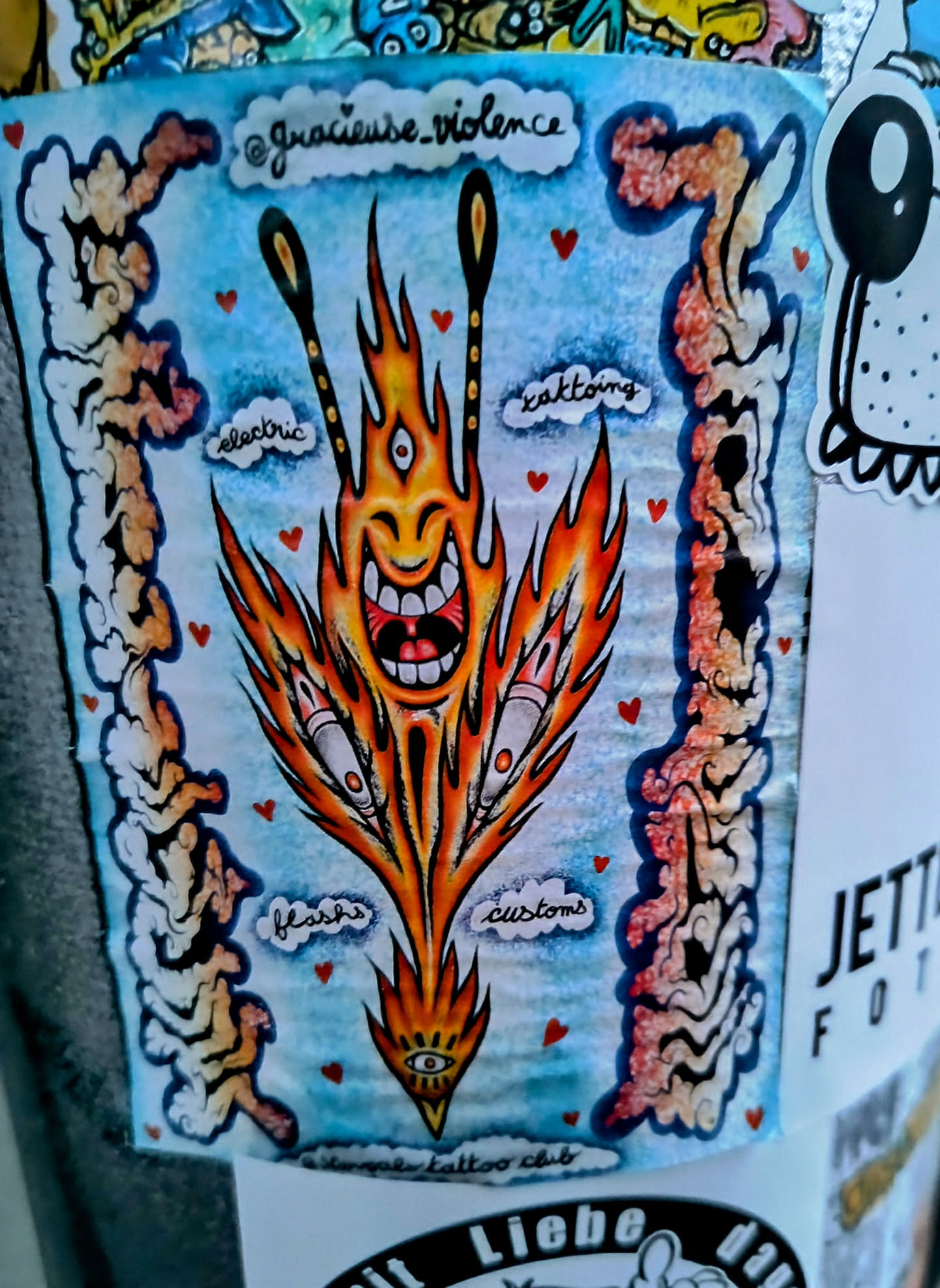 A vibrant sticker featuring a cartoonish flaming creature with three eyes and a joyful expression.  The design includes the words "electric", "kaktong", "flashes", and "customs" in cloud-like shapes surrounding the main figure.  The artist's Instagram handle is visible at the top. The sticker also states that it is part of the "Simple Tattoo Club".