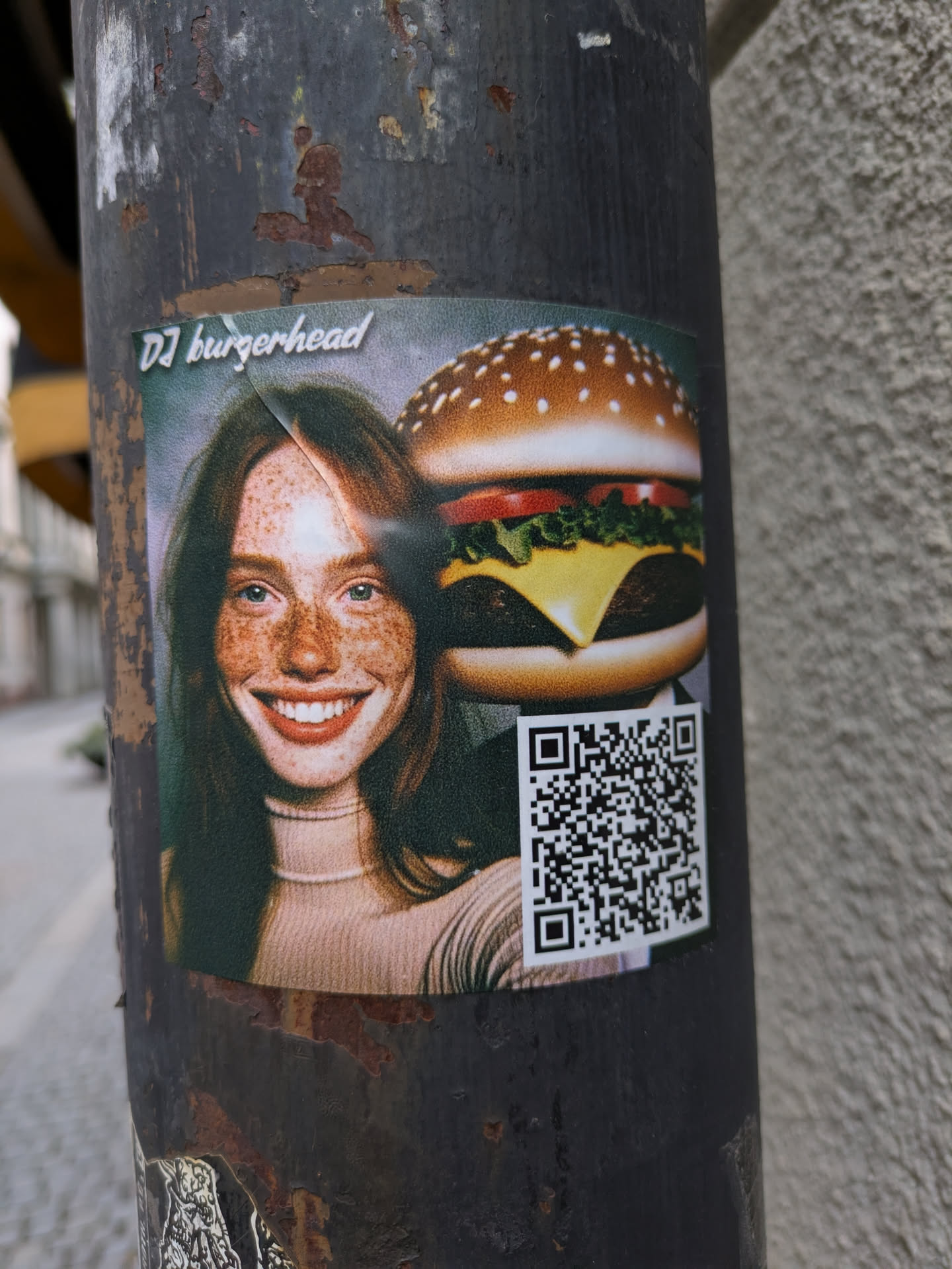 A sticker featuring a woman and a burger. The text on the sticker says DJ burgerhead. There is a QR code on the sticker.