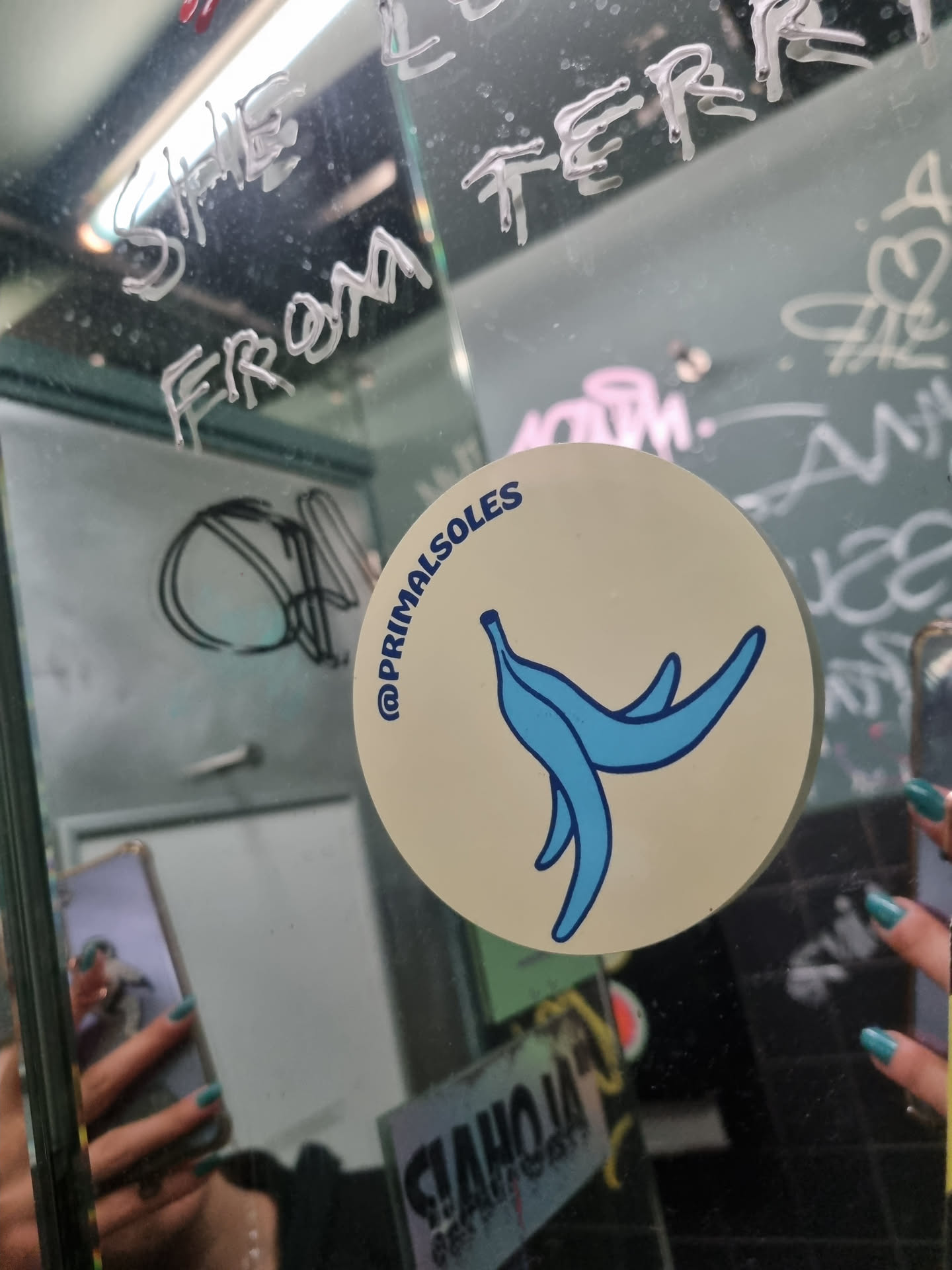 Round beige sticker with a blue peeled banana illustration and the social media handle @primalsoles.