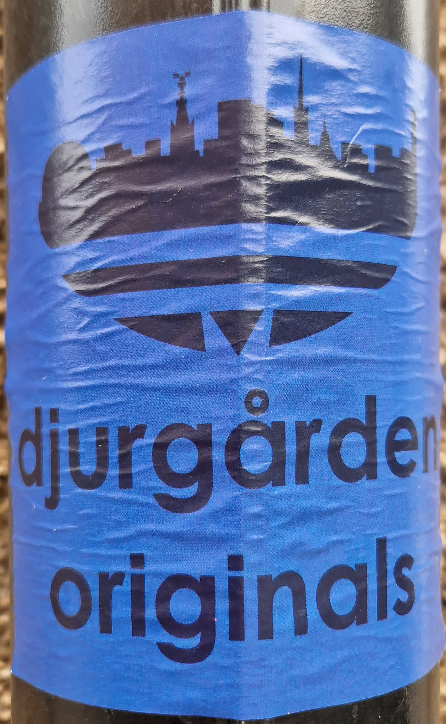 A blue sticker with a black silhouette of a city skyline and the text "Djurgården Originals".
