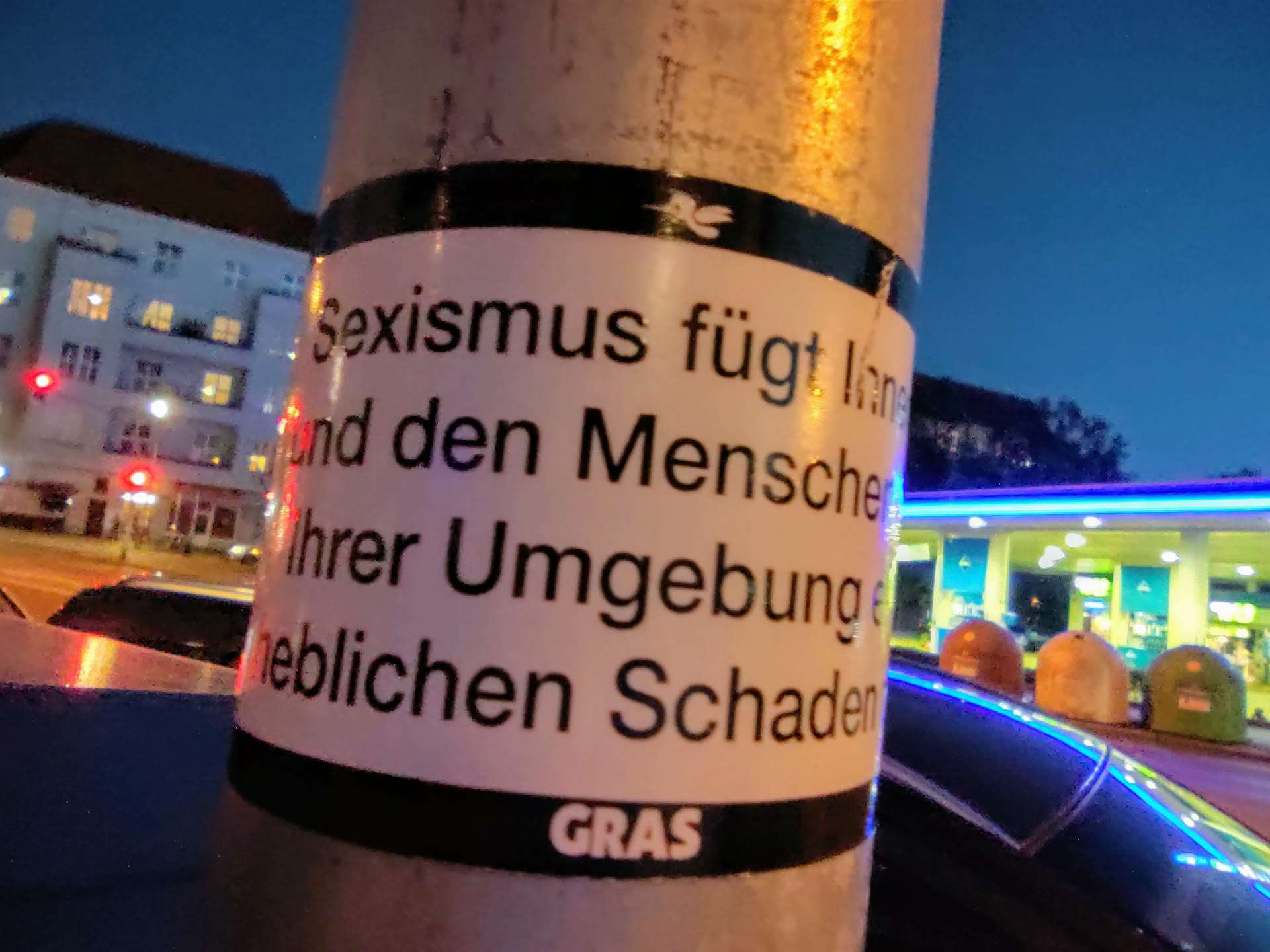 A sticker on a pole with text in German that translates to: "Sexism causes long-term damage and significant harm to people and their environment."