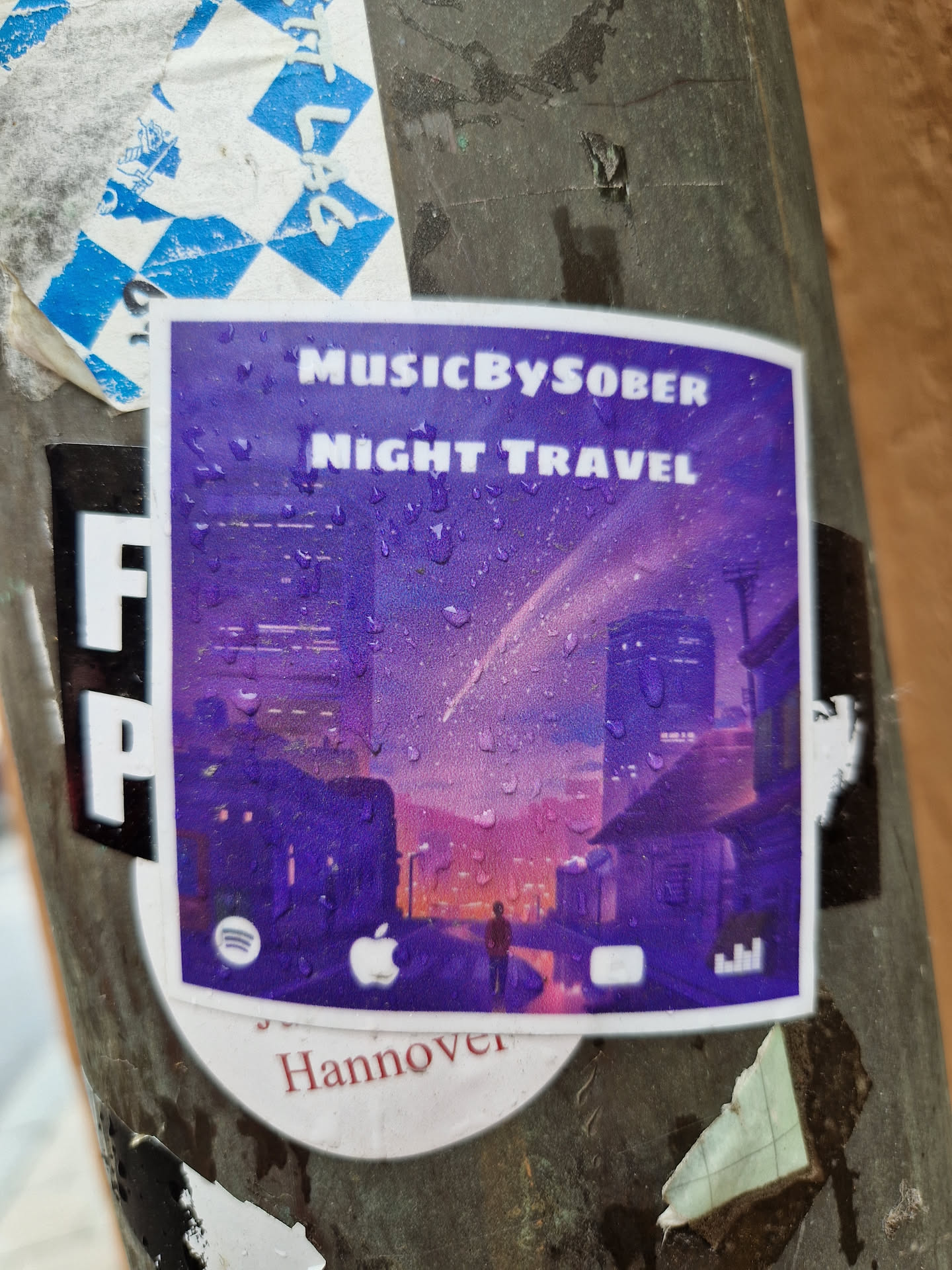 A purple sticker featuring an illustration of a city street at night, with rain drops visible on the surface. The artist's name 'MusicBySober' and album title 'Night Travel' are prominently displayed.  Social media links for Spotify, Apple Music, and YouTube Music are shown at the bottom, along with the location 'Hannover'.