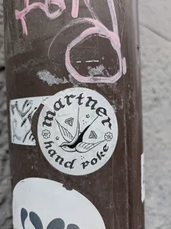 A round sticker with a swallow and diamonds in the center. The text around it says 'Marther hand poke'.