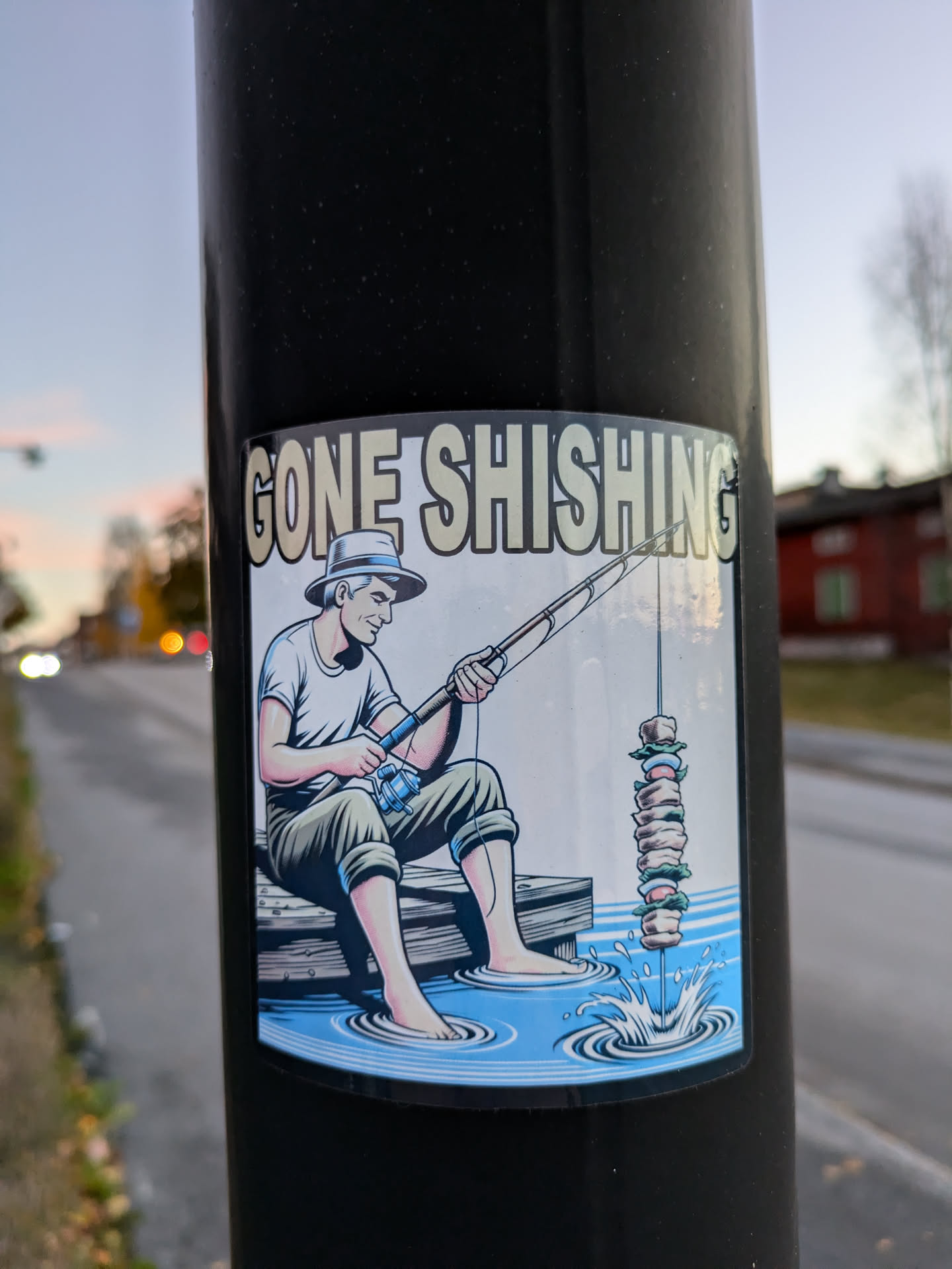 A sticker depicting a man fishing, but instead of a fish, he's catching a shish kebab. The text 'Gone Shishing' is at the top.