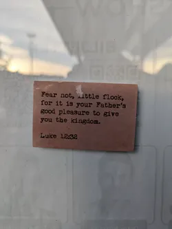 A small, light brown sticker with a bible verse from Luke 12:32. The text is typed in a typewriter style font.