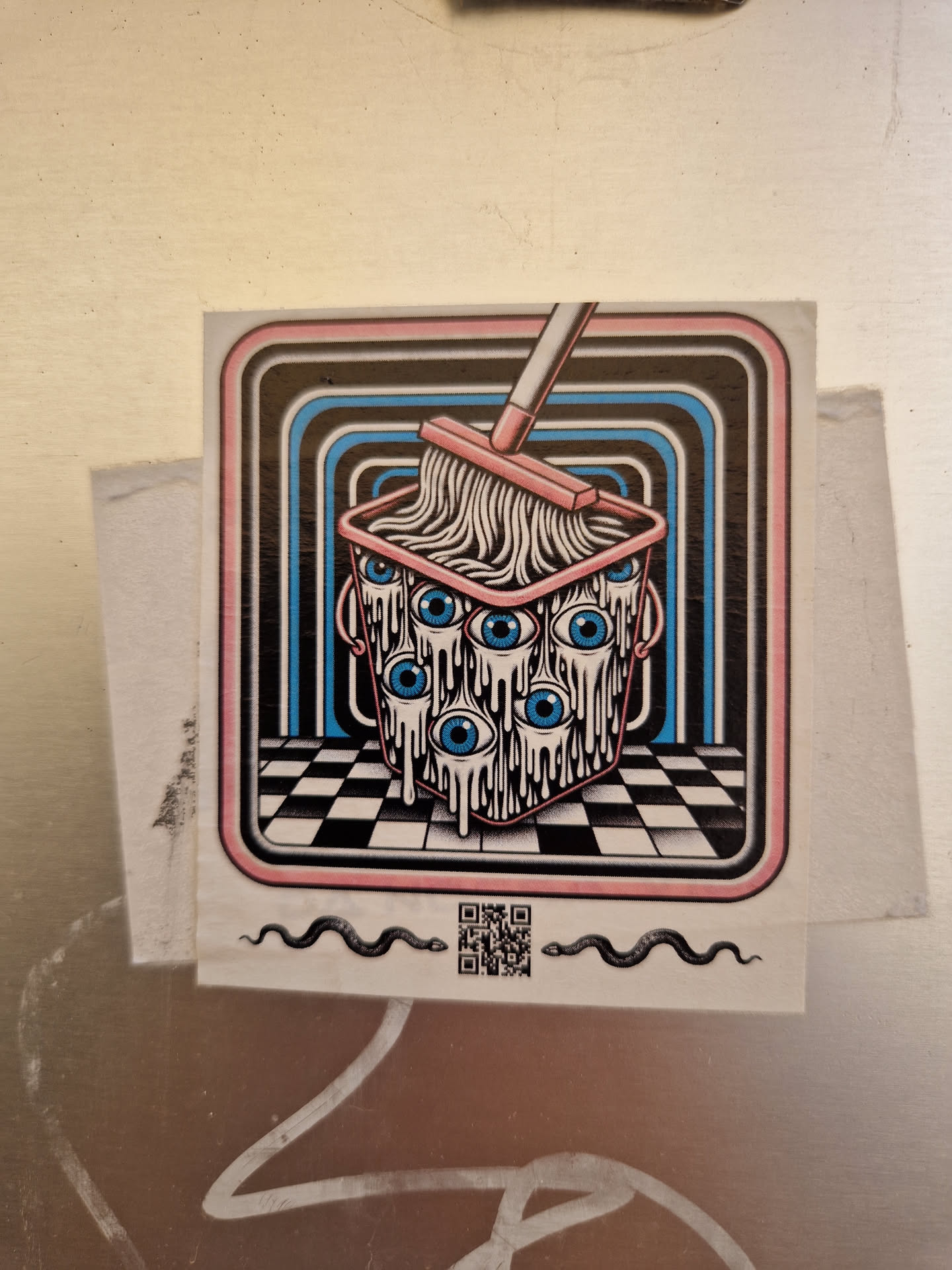 A sticker featuring a bucket with eyes being mopped. The design is in a retro style with a checkerboard floor and concentric circles in the background.  Two snakes flank a QR code at the bottom.