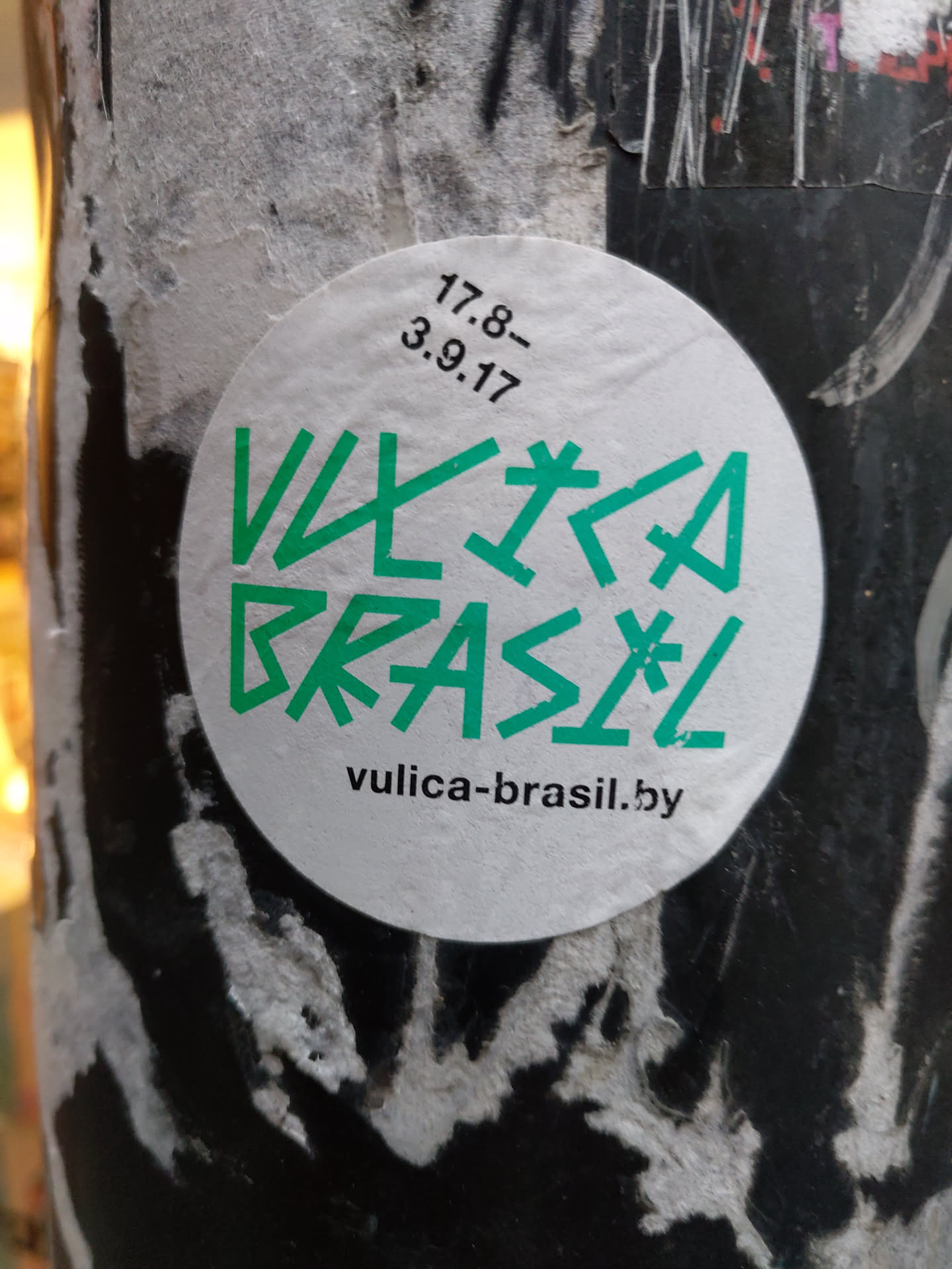 Round white sticker with green text. The text says "Vulca Brasil" in a stylized font.  There are also some small numbers and date written on the sticker, "17.8- 3.9.17", possibly indicating creation or release date. Below the main text, there is a website address: vulica-brasil.by