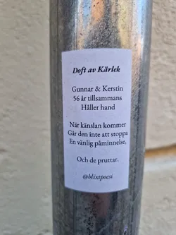 A small white sticker on a metal pole with a poem about love, Gunnar and Kerstin, who have been together for 56 years.  The poem mentions a feeling that cannot be stopped and ends with a humorous observation.