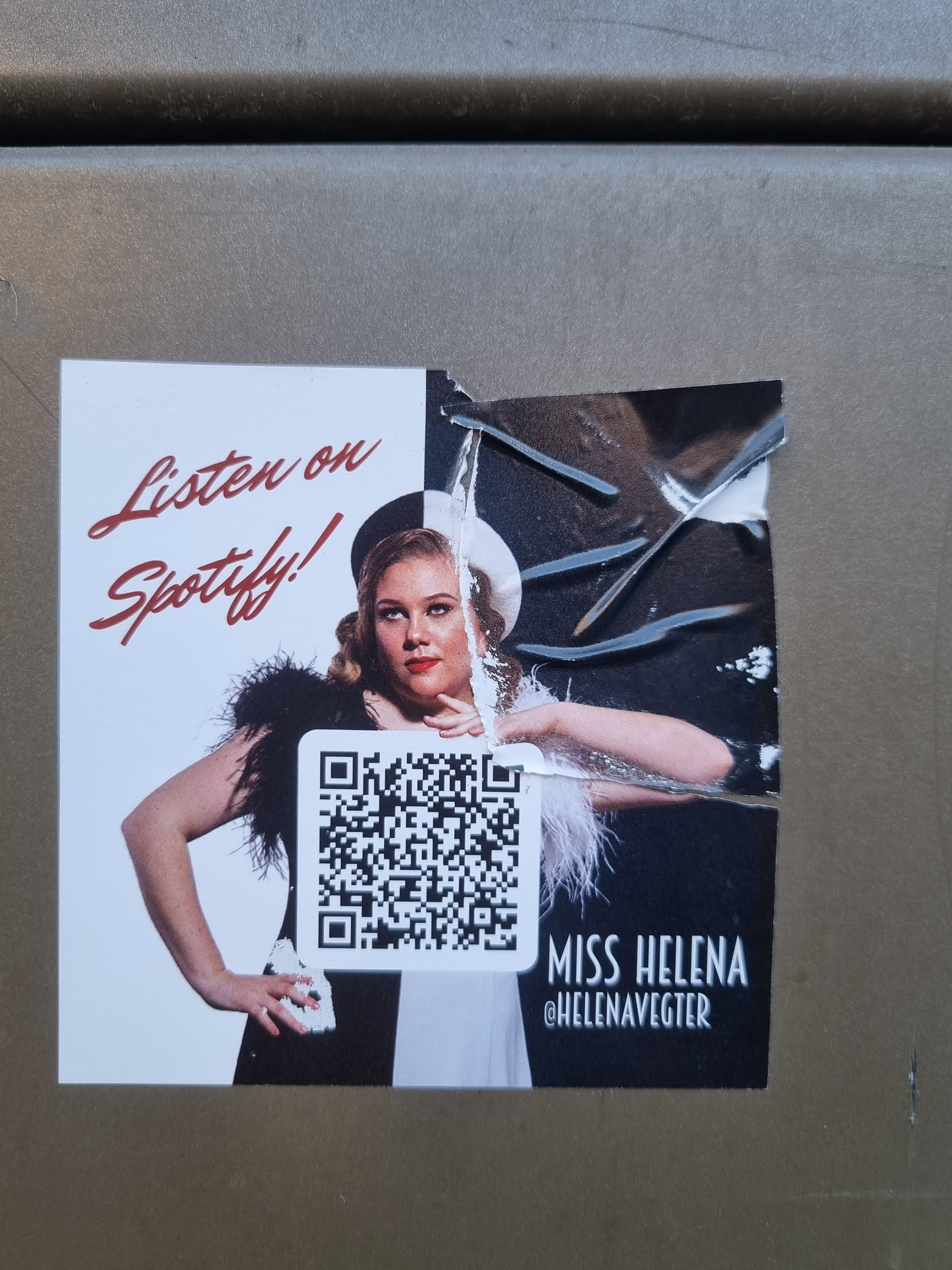 A sticker featuring a woman in a vintage style dress with a QR code linking to her Spotify profile. The text on the sticker says "Listen on Spotify!" and includes her artist name and Instagram handle.