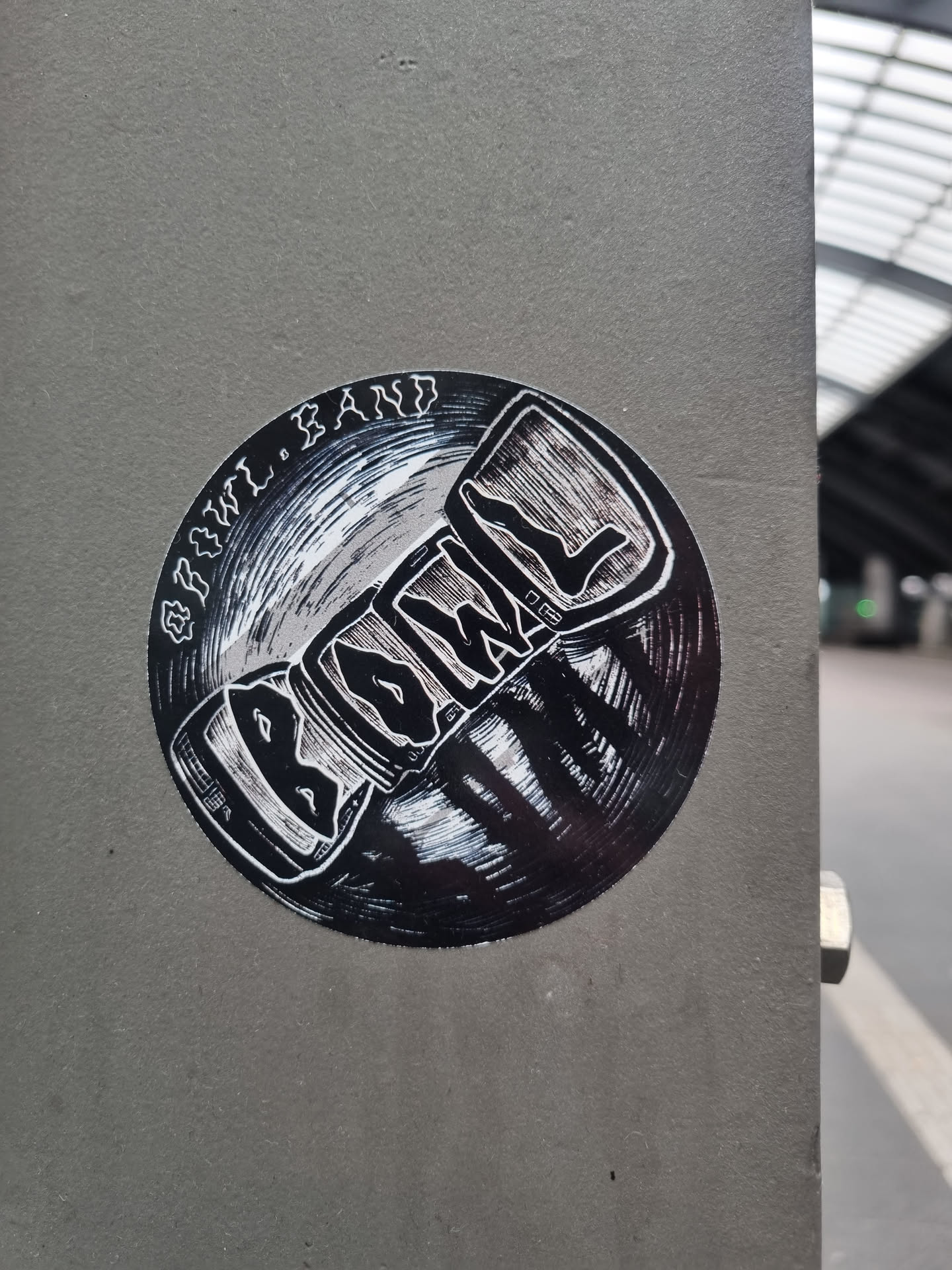 Round black and white sticker with the band's name Biowül and the words "Biowül Band" written around it. It features a stylized illustration that looks like a record or a similar object.