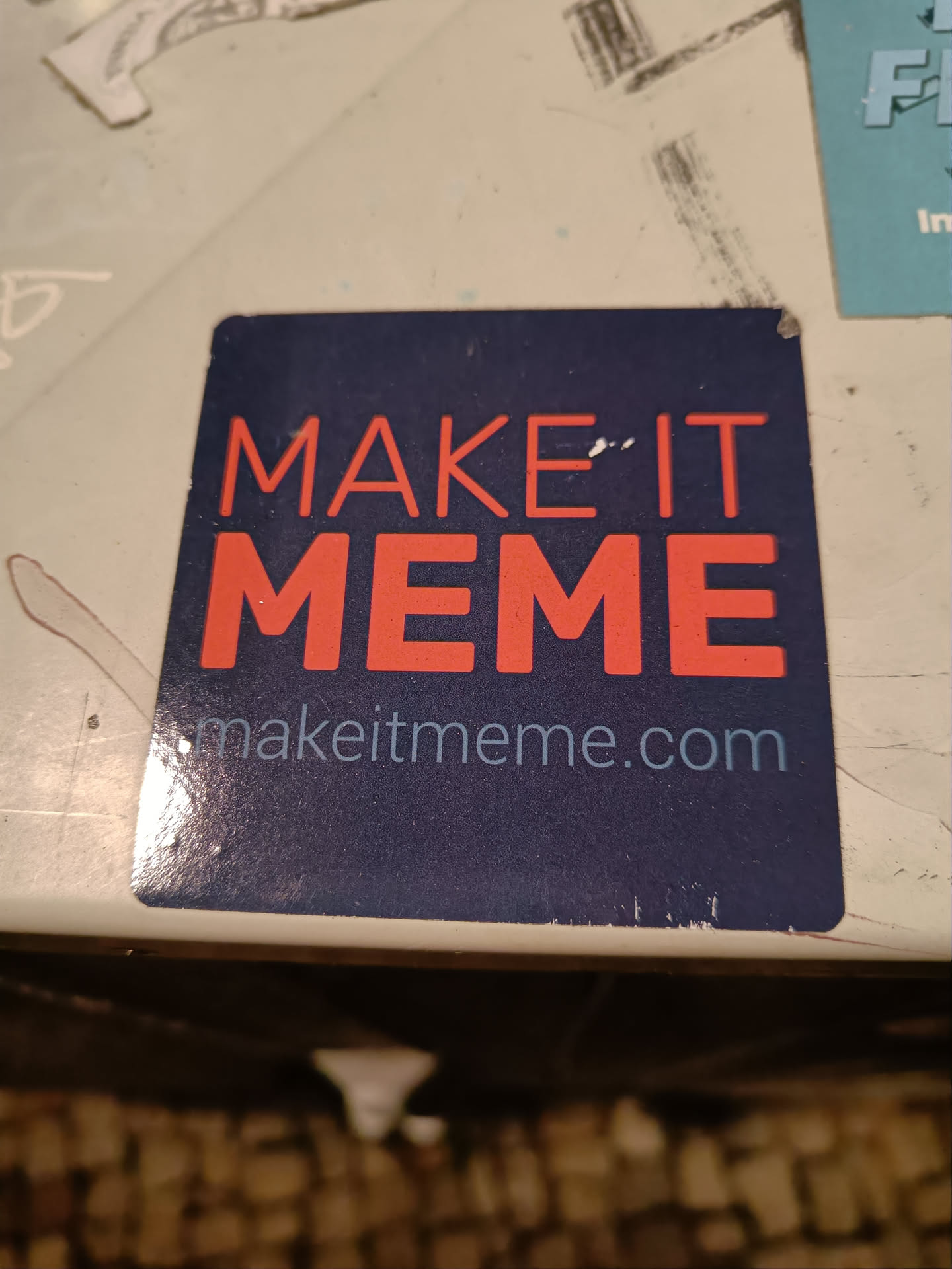 A dark blue sticker with the text "MAKE IT MEME" in red and the website address makeitmeme.com at the bottom.