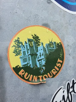 Round sticker featuring an illustration of a ruined building, trees, and the text "Ruin Tourist".