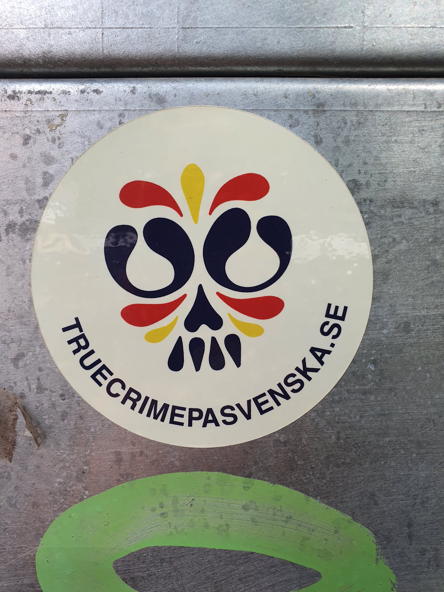 Round sticker with a stylized skull design in red, yellow, and dark blue. The text "truecrimepasvenska.se" circles the skull graphic.