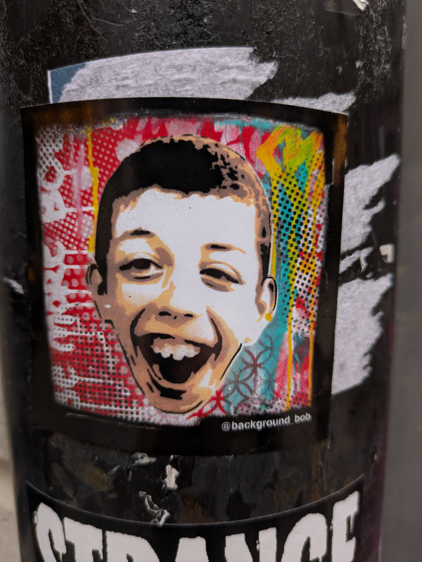 This sticker is a bold piece of street art. The child's expression is joyful and energetic, and the contrasting colors create a striking visual effect. The artist's signature adds a personal touch.