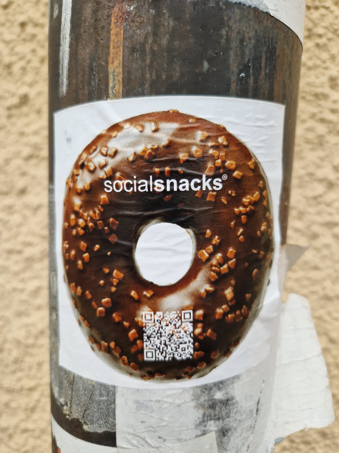 A sticker featuring a delicious-looking chocolate donut with sprinkles. The brand name "socialsnacks" is printed on the donut. A QR code is also present on the sticker.