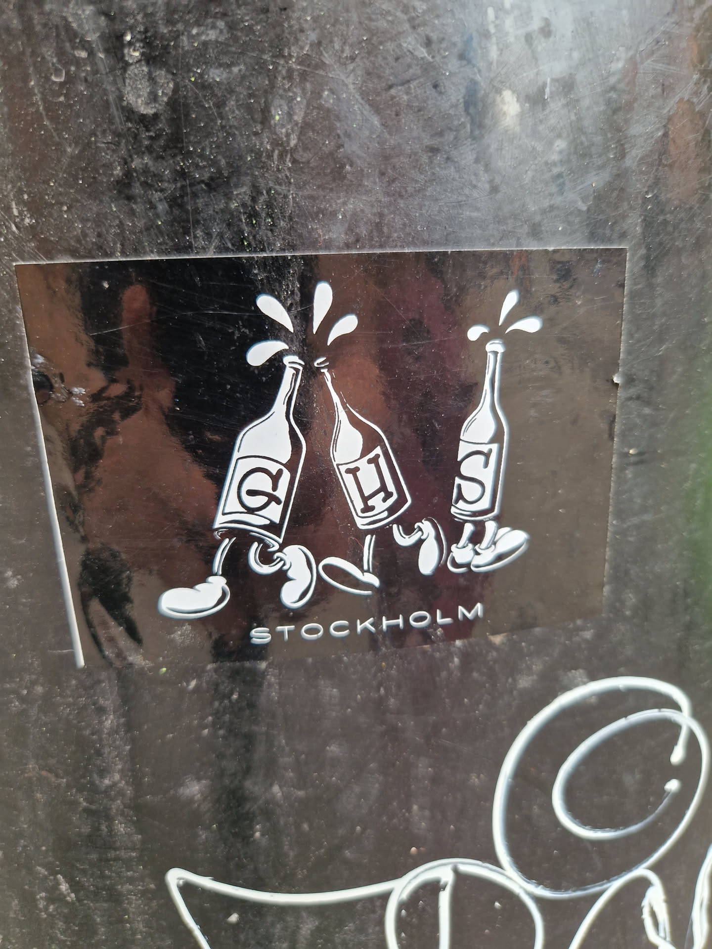 A sticker featuring three anthropomorphic bottles walking, with the word "STOCKHOLM" written below. The bottles appear to be pouring liquid.