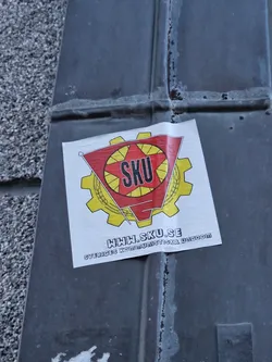 A sticker featuring the logo of Sveriges Kommunistiska Ungdom (SKU), the Swedish Communist Youth. The logo includes a red star and gear with the acronym SKU. The website www.sku.se is also displayed.