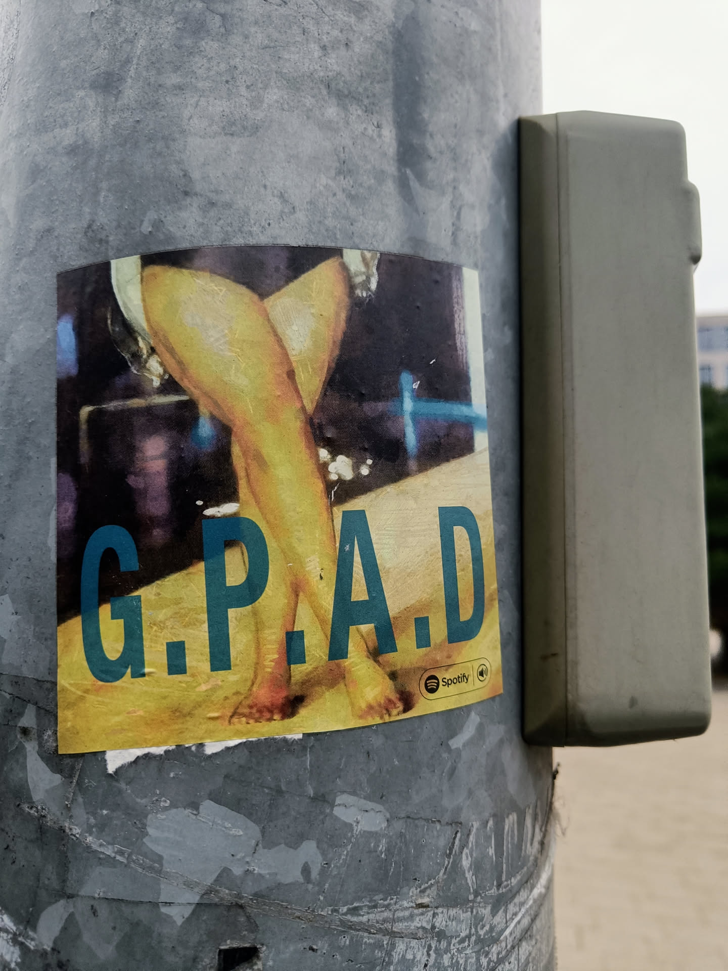 A sticker featuring a pair of crossed female legs with the acronym G.P.A.D printed on it. The sticker has a Spotify logo on the bottom right corner.