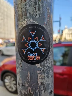 A sticker for Teo's Tonics, an alcohol shop located in Bucharest, Romania.  The sticker features a geometric design with a dark background and neon-colored accents.  The shop's name and address are clearly visible.