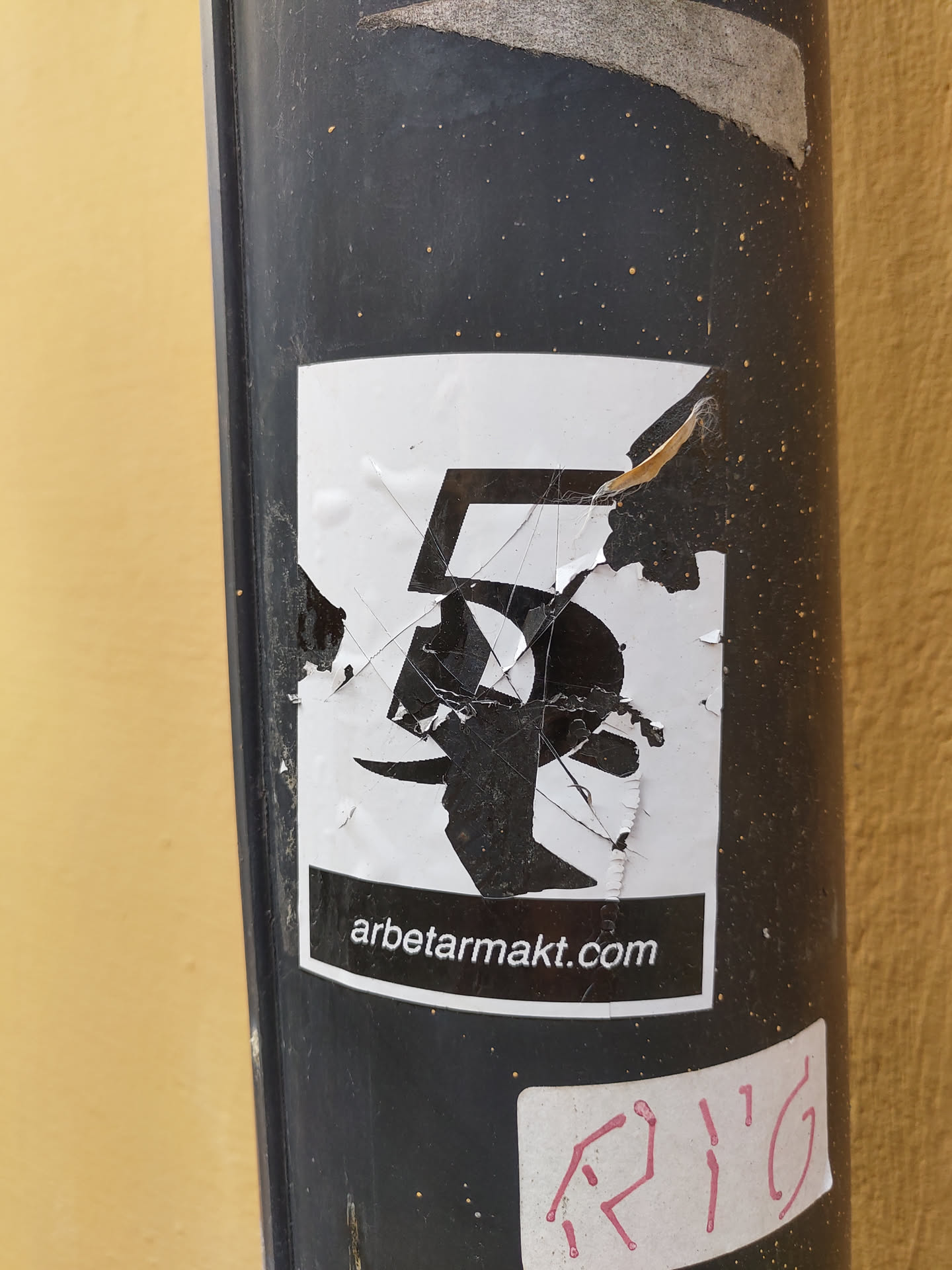 The sticker is partially damaged and shows a stylized number 5.  The website arbetarmakt.com is visible at the bottom. The sticker is affixed to a dark-colored pole.