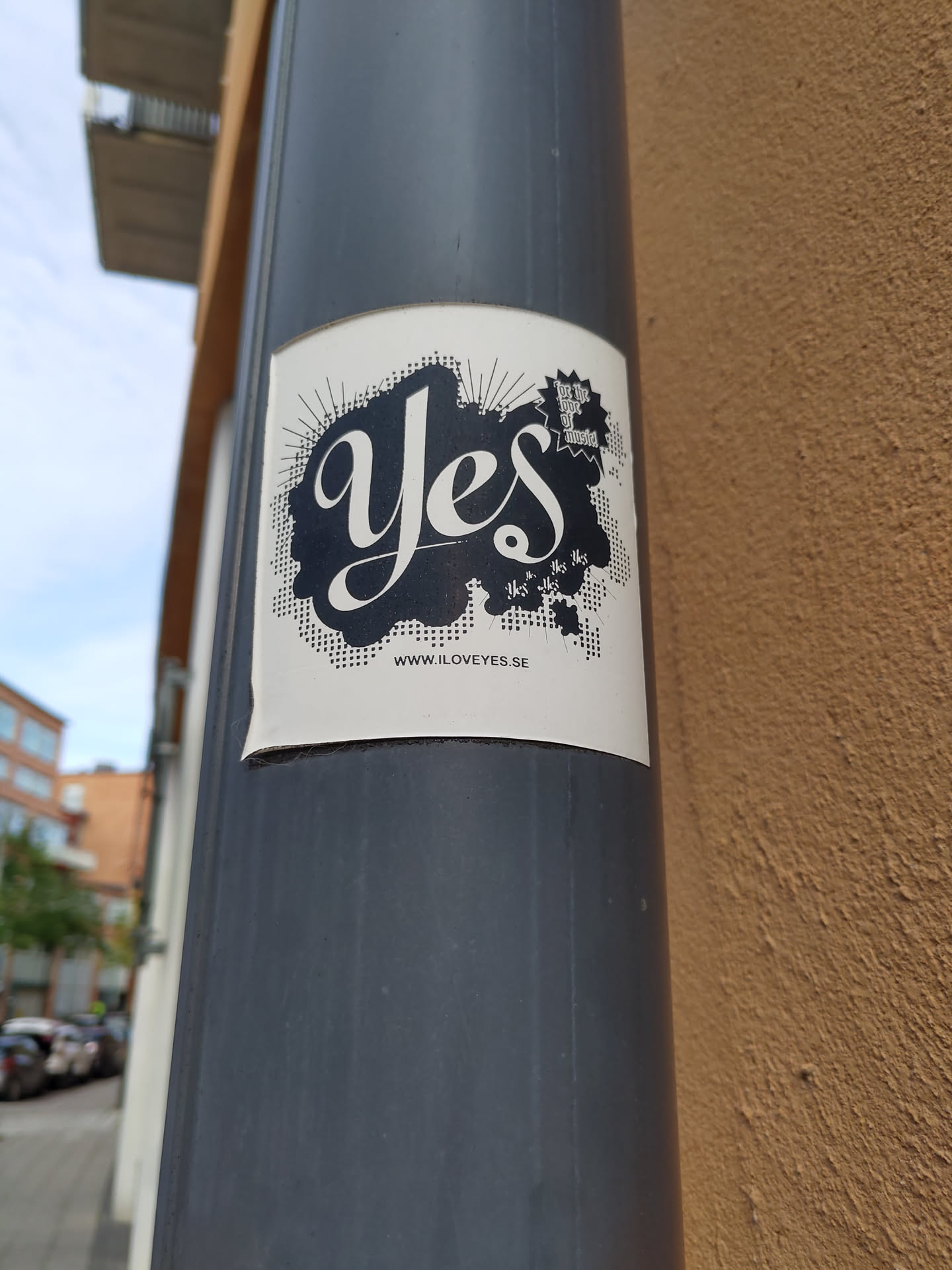 A minimalist sticker featuring the word "Yes" in a stylized script font, set against a halftone background with burst lines.  There is a small logo or design element near the top right, and a website address at the bottom. The overall aesthetic is clean and modern.