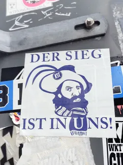 A sticker featuring a stylized illustration of a man with a beard wearing a hat, accompanied by the German phrase "Der Sieg ist in uns!" which translates to "Victory is within us!"