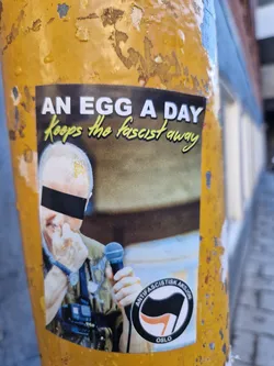 A sticker featuring a photo of a person with their face partially obscured, holding a microphone.  The text 'An egg a day keeps the fascist away' is at the top. The Anti-fascistisk aksjon Oslo logo is at the bottom.