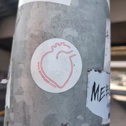 A white circular sticker with a red line drawing of a heart. The website address www.annaluppi.com is printed in small red text beneath the illustration.