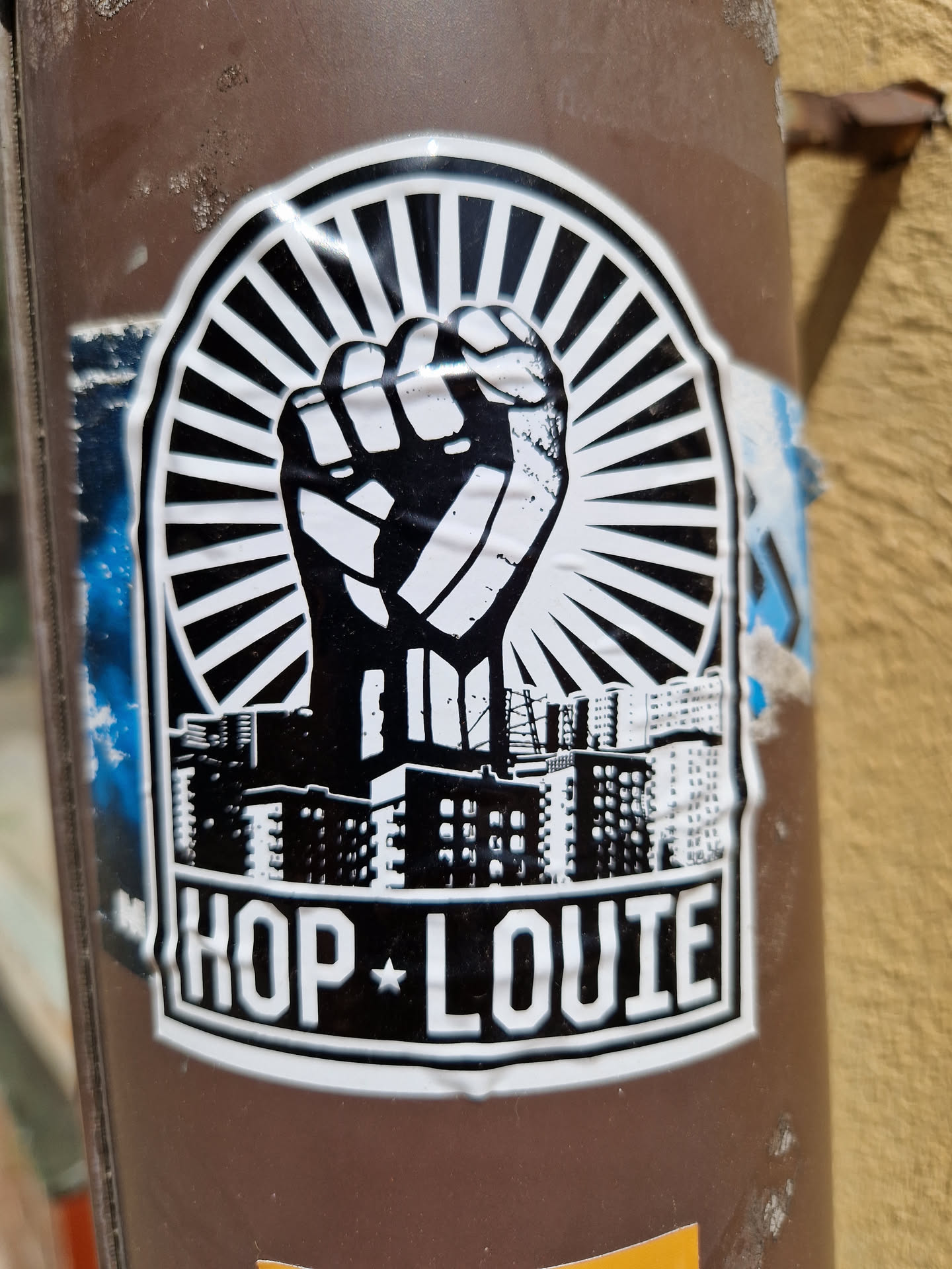 A black and white sticker with a graphic of a raised fist and cityscape, with the text "HOP*LOUIE" underneath.