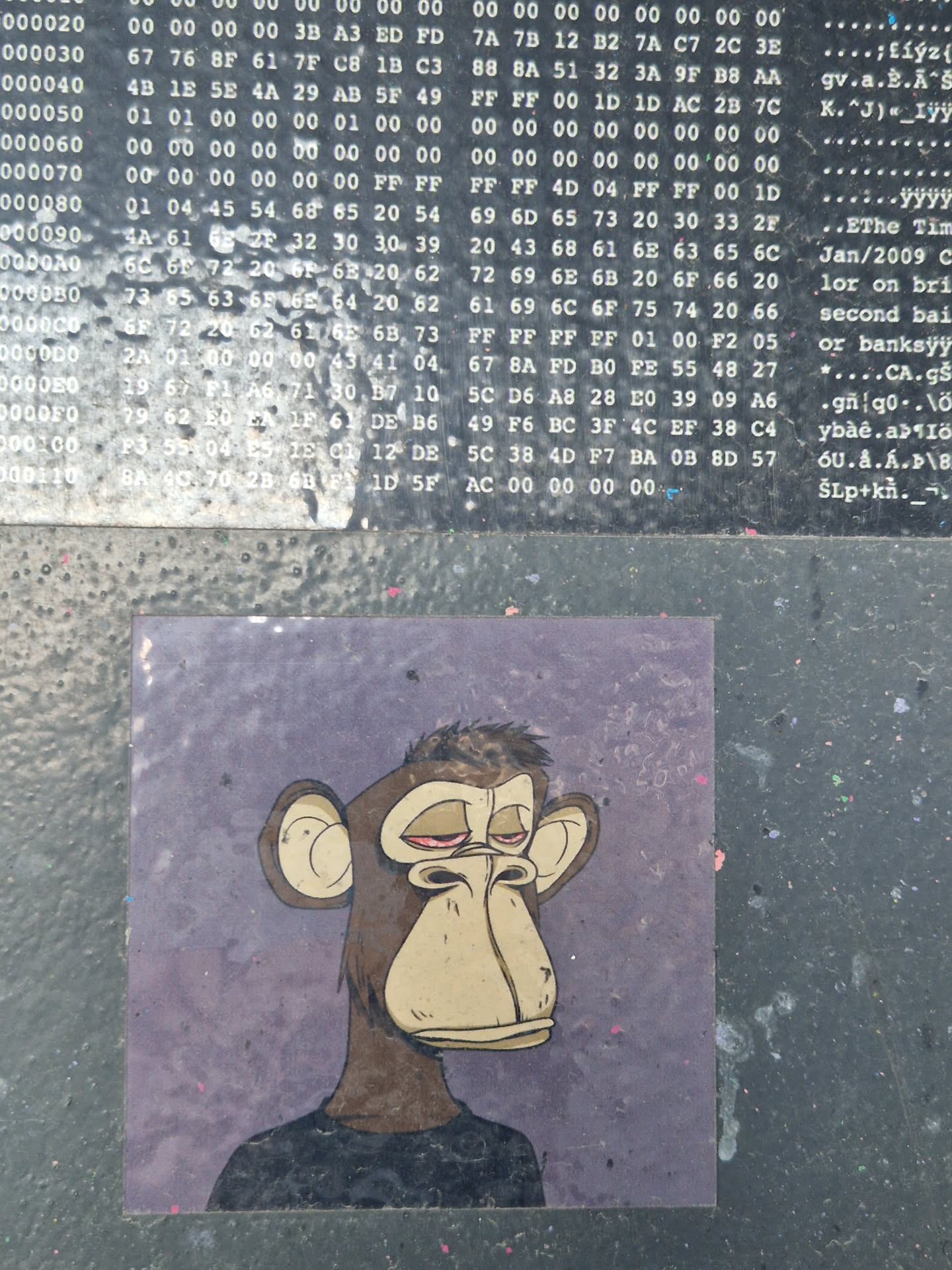 The sticker features a brown cartoon monkey, characteristic of the Bored Ape Yacht Club (BAYC) NFT collection, against a mottled purple background. The ape has a slightly droopy, melancholic expression with red-rimmed eyes and a prominent snout. It is depicted wearing a simple black t-shirt. The artwork is in a stylized, flat-color comic or cartoon aesthetic.