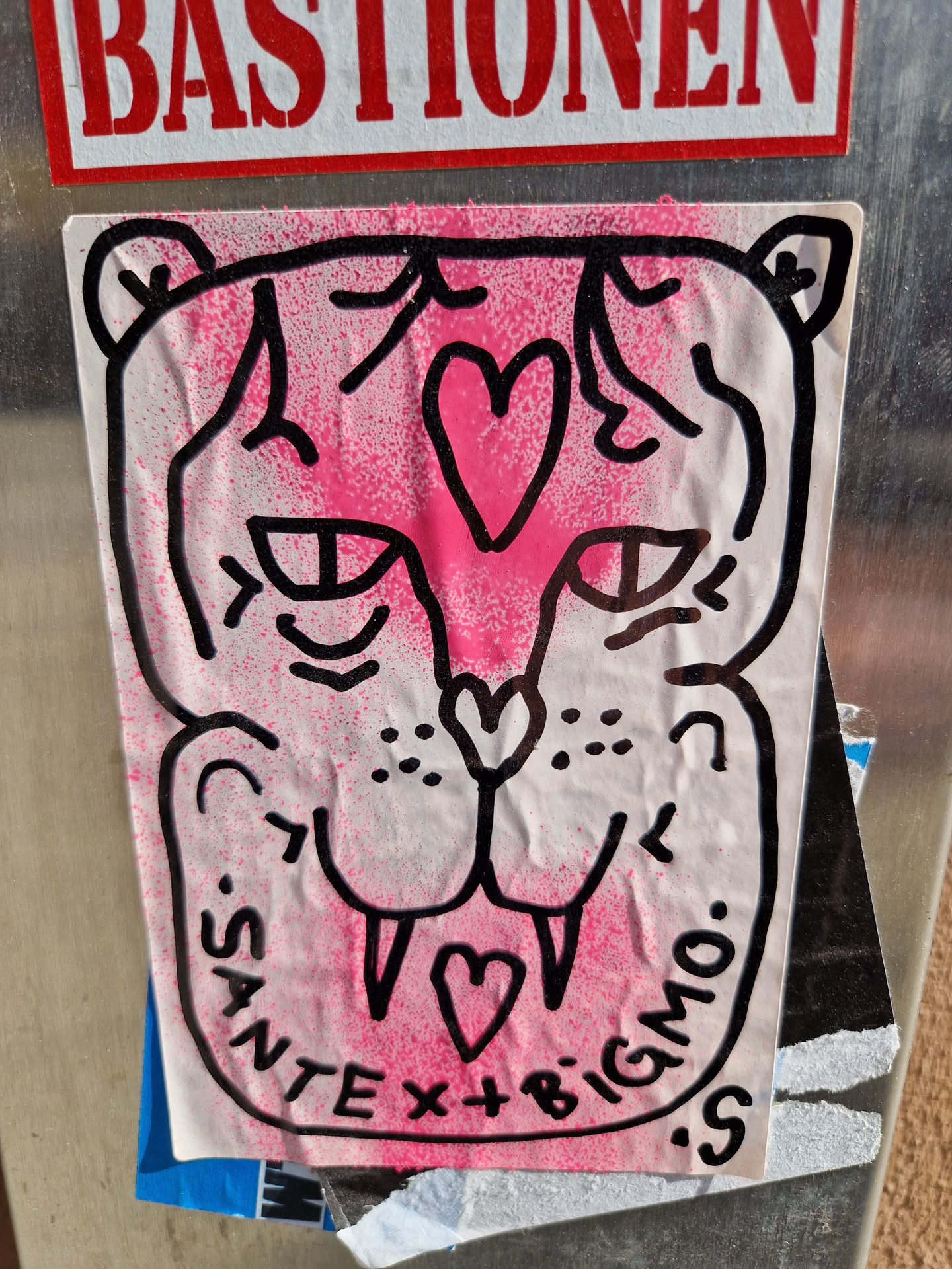 A pink and black drawing of a tiger's face with two hearts. The text at the bottom says "SANTE x BIGMO".