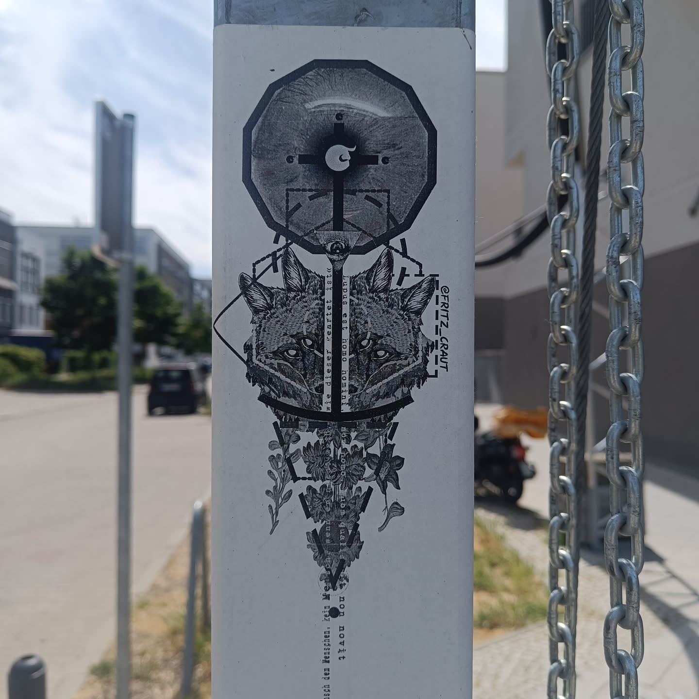 Black and white sticker featuring a geometric design with two fox heads, a compass-like element, and floral details. The artist's signature, Fritz_kraut, is visible in the corner. 