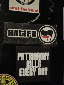 A black and white sticker with the text "Patriarchy Kills Every Day" in bold, uppercase letters.  There is a smaller Antifa sticker above it, featuring the Antifa symbol.