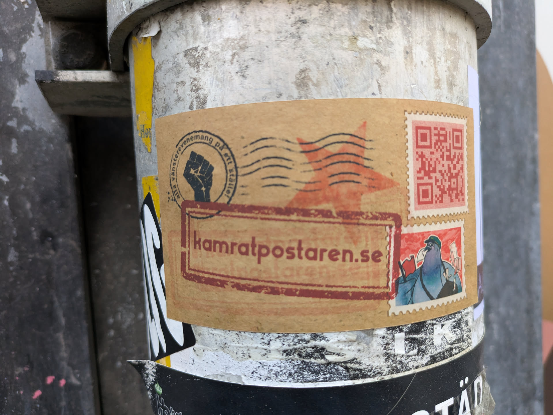 A sticker featuring the KamratPosten website address, a QR code, and various stamps. The aesthetic is reminiscent of vintage postal stamps with a rebellious twist. The main text reads 'kamratposten.se'.