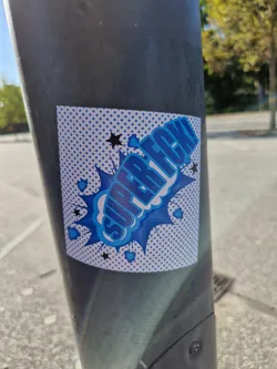 A blue and white sticker with the text "Super Rec!" in a comic book style. It is affixed to a dark gray pole.