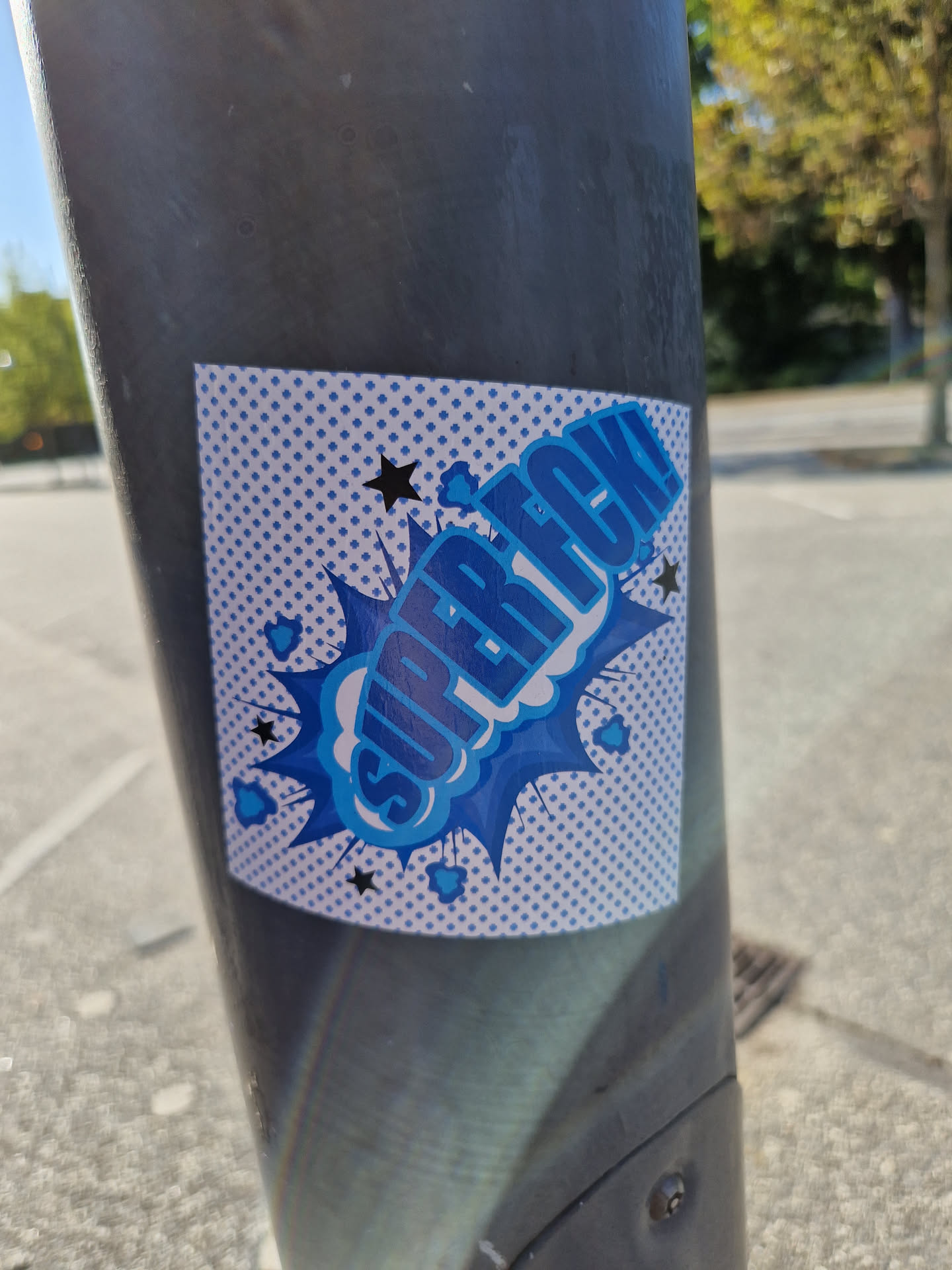 A blue and white sticker with the text "Super Rec!" in a comic book style. It is affixed to a dark gray pole.