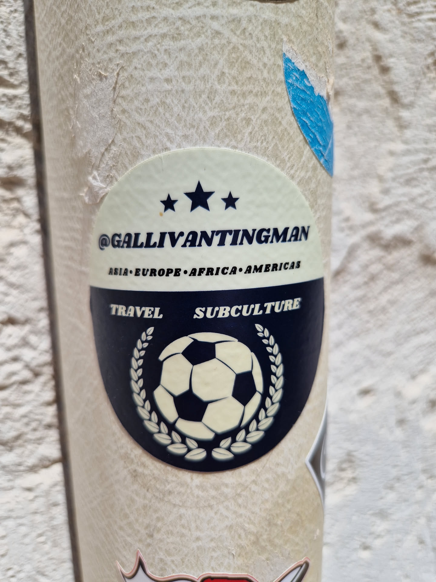 Round sticker with a soccer ball in the center, surrounded by a laurel wreath.  Text on the sticker includes '@GallivantingMan', 'Asia Europe Africa Americas', 'Travel', and 'Subculture'. Three stars are present above the main text.