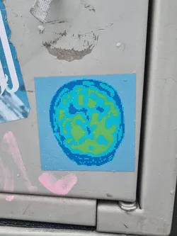 A sticker featuring a pixel art design of a brain in shades of blue and green on a light blue background.