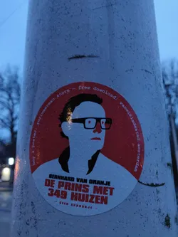 A round sticker featuring an illustration of Bernhard van Oranje with text that translates to "Bernhard of Orange - The Prince with 349 Houses" and  "Not a fairytale". It also mentions a website/store and a free download.