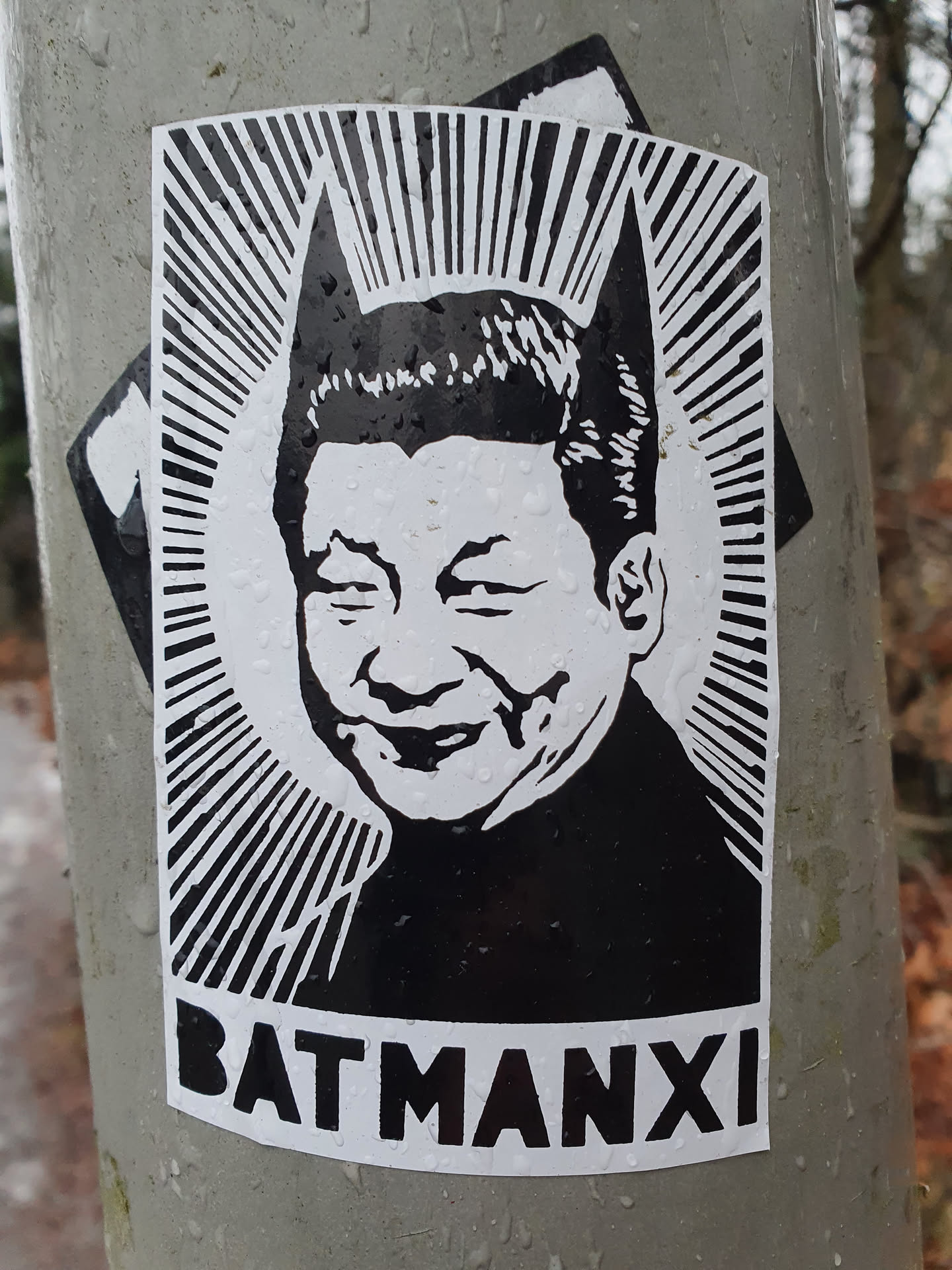 Black and white sticker depicting Xi Jinping with Batman ears. The text at the bottom reads "BATMANXI".