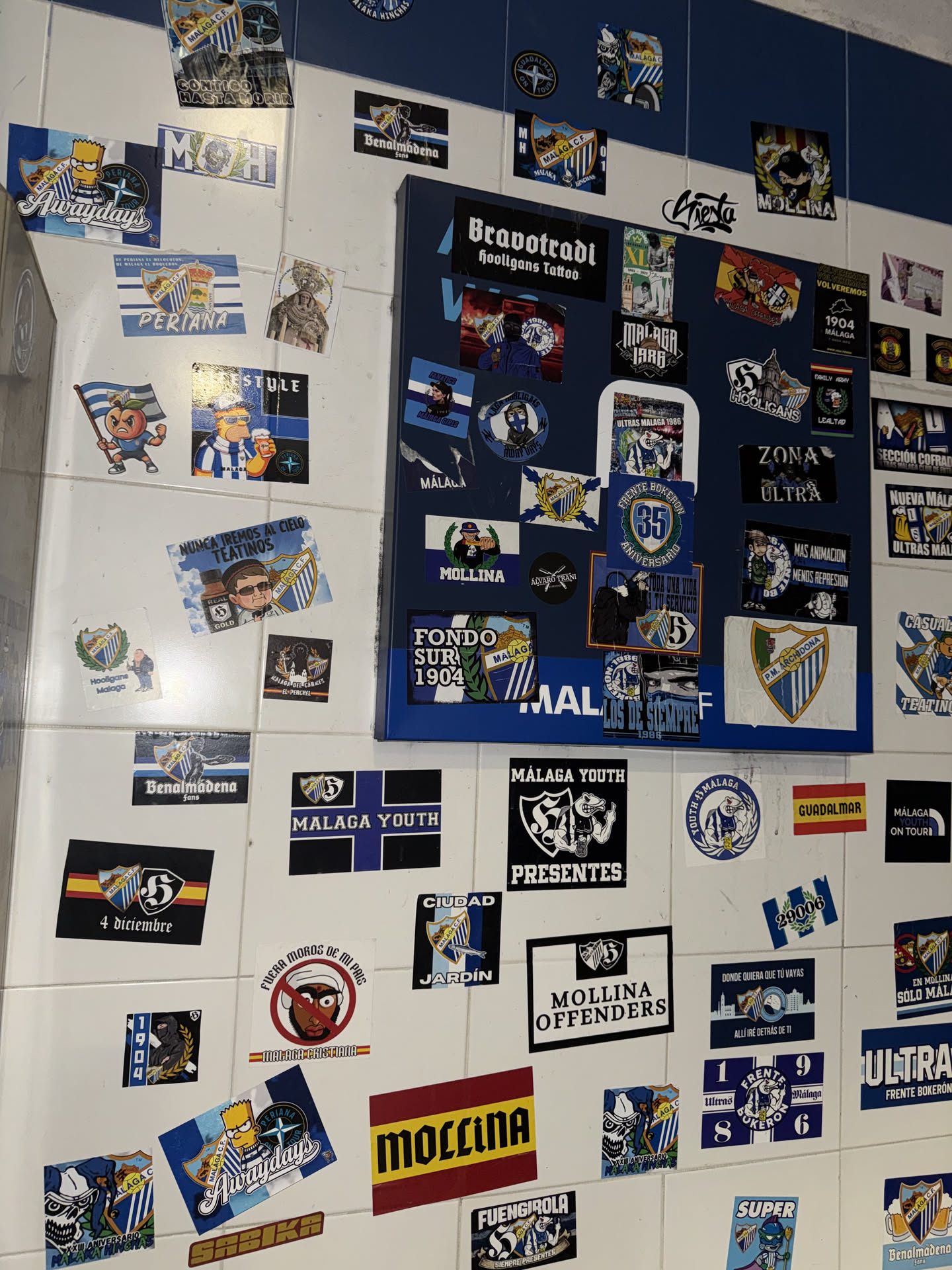 The sticker is circular, predominantly blue and white, with yellow/gold accents. In the center, it features a stylized, somewhat aggressive-looking figure, possibly a mascot or a fan, wearing a blue and white striped shirt and a cap, holding what appears to be a flag or banner. The figure is set against a background that includes elements resembling a shield or crest, typical of football clubs. Around the central figure, the text "FRENTE BOKERON" is prominently displayed in an arc at the top, and "35 ANIVERSARIO" is written below, indicating a 35th anniversary. There are also smaller details and patterns within the design, contributing to a dynamic and spirited appearance.