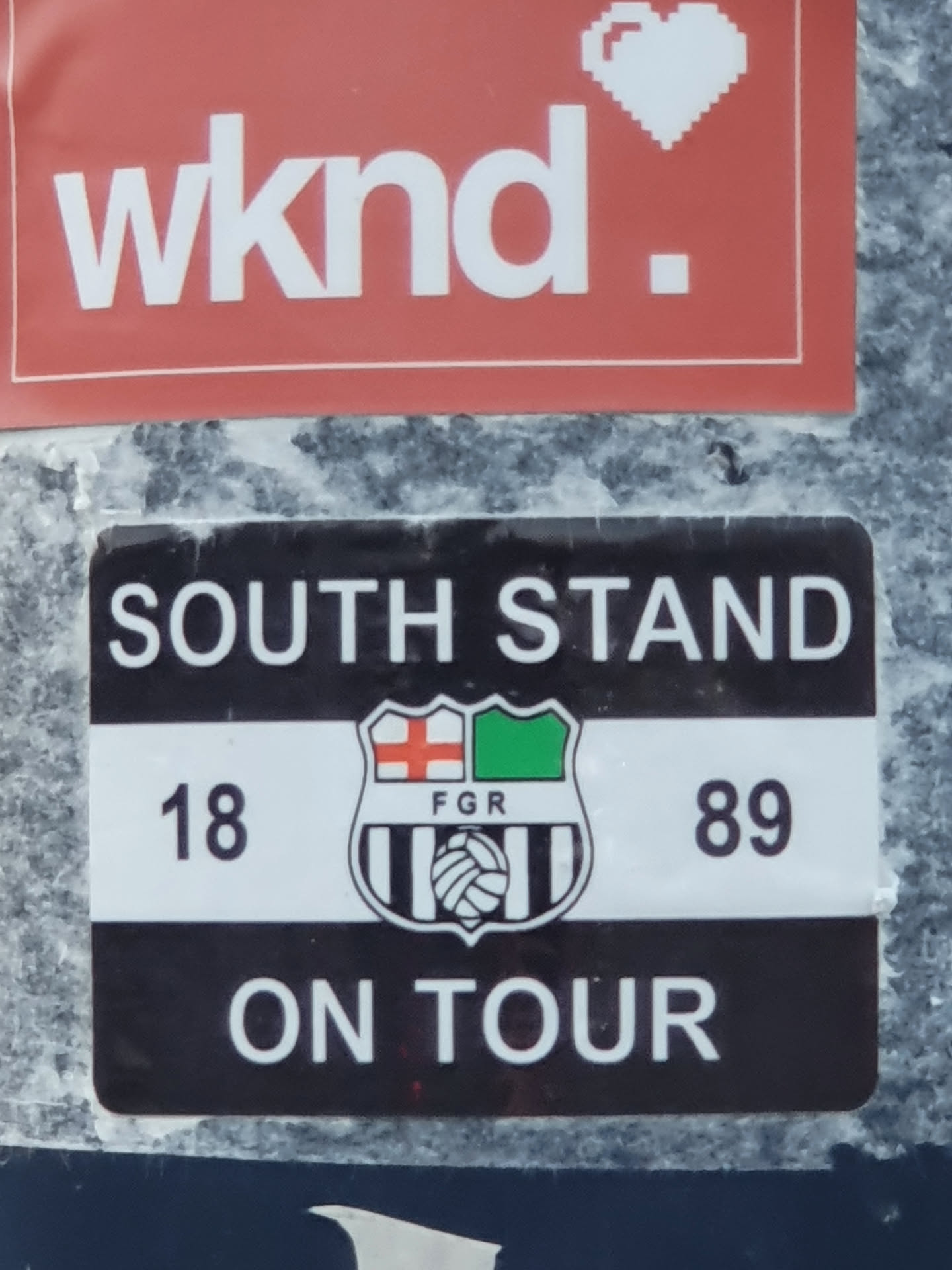 A black and white sticker with a crest and the text 'SOUTH STAND', '18', '89', and 'ON TOUR'. The crest features a shield with red and green sections, and a football.