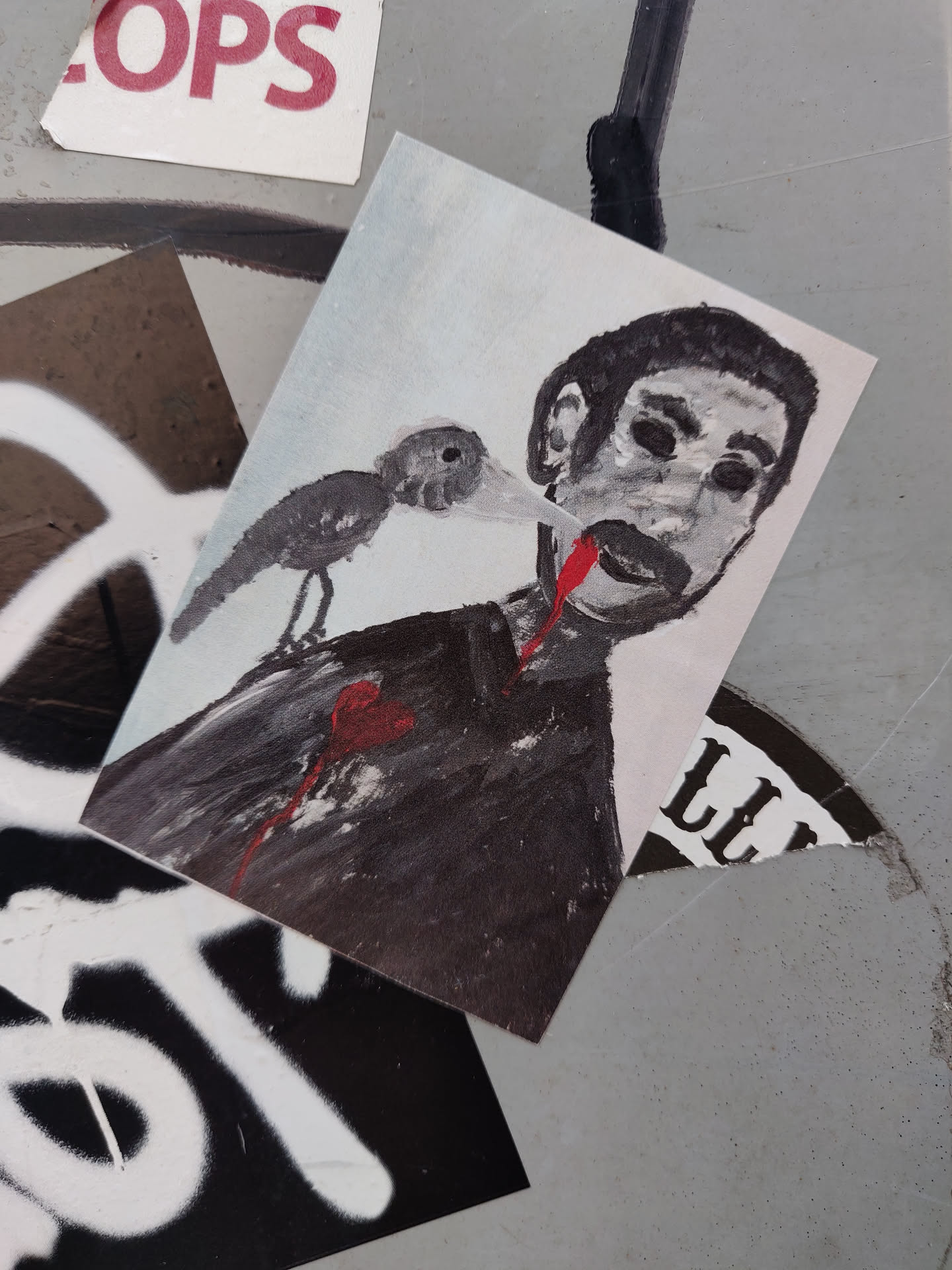 A sticker with a dark, slightly gory illustration of a man with a bird seemingly sucking his blood. The style is reminiscent of dark art or surrealism.  The sticker is rectangular and printed on what appears to be matte sticker paper.